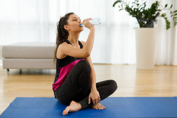 istock Woman drinking water while practicing yoga at home 1226929623