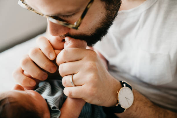 Father is kissing his son little hands