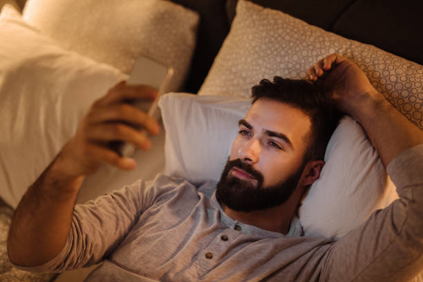 istock Handsome bearded man using phone in the bed at night 1226932128