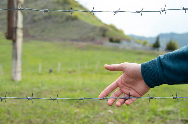 istock man hand and barbed wire in landscape 1226932179