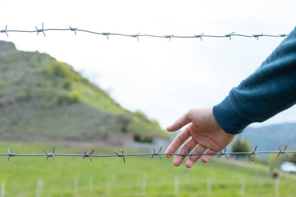 istock man hand and barbed wire in landscape 1226932196