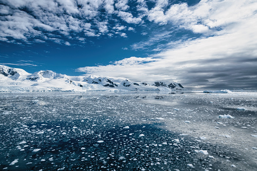 Antarctica Peninsula Glaciers and Mountain Range under blue skyscape in summer. Small Icebergs and Icesheets floating on the half frozen calm Antarctic Ocean. Antarctica Peninsula, Antarctica