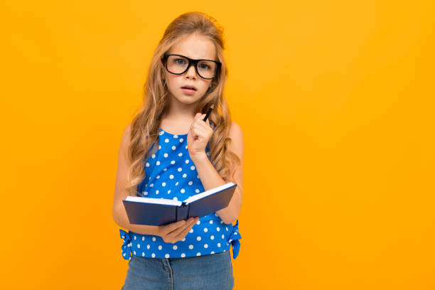 istock Nice little girl with her glasses holds a notebook isolated on white background 1226942929