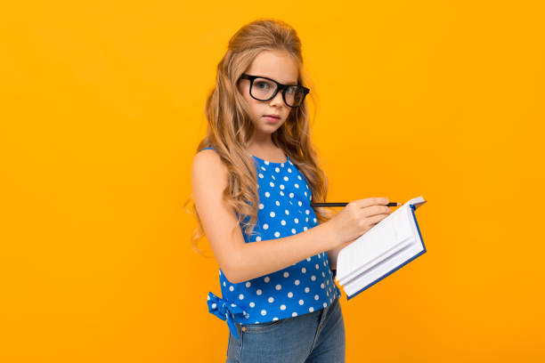 istock Nice little girl with her glasses holds a notebook isolated on white background 1226942944
