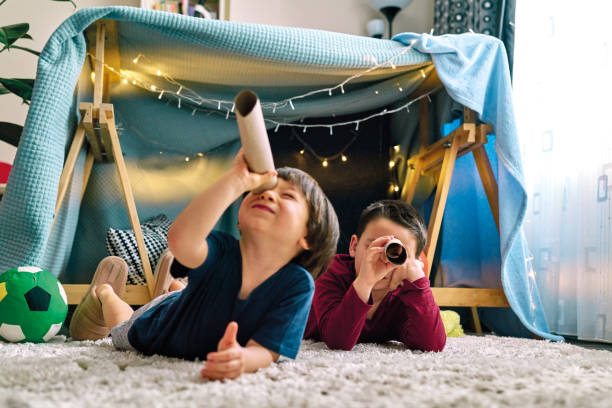 dwoje uroczych dzieci robi obóz i bawi się razem w namiocie w domu - little boys discovery binoculars child zdjęcia i obrazy z banku zdjęć