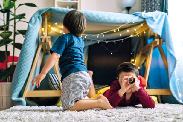 istock Two cute children making a camp and playing together in tent at home 1226946721