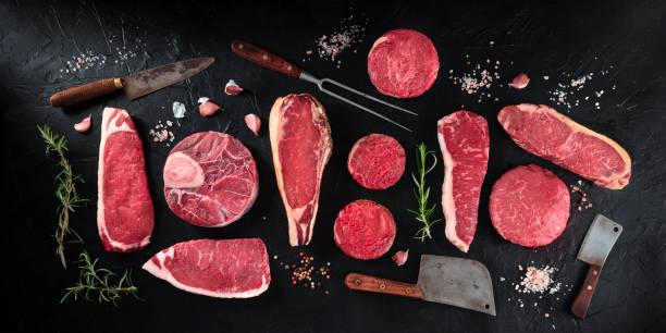 Cuts of meat panorama, shot from the top on a black background with salt, pepper, rosemary and knives, a flat lay Cuts of meat panorama, shot from the top on a black background with salt, pepper, rosemary and knives, a flat lay carving set stock pictures, royalty-free photos & images