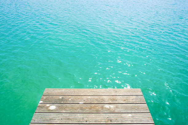 Summer background, wooden footbridge on swimming lake with turquoise water