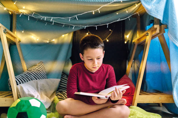 istock Cute child making a camp and reading book in tent at home 1226952413