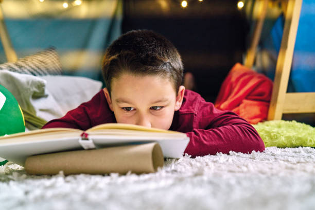 istock Cute child making a camp and reading book in tent at home 1226954052