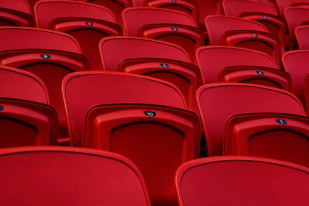 istock Empty red plastic seats in an empty stadium. Many empty seats for spectators in the stands. Empty plastic chairs seats for football fans. 1226954175
