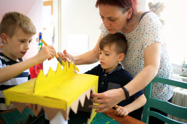 istock Mother helping boys to paint a carboard project 1226954814