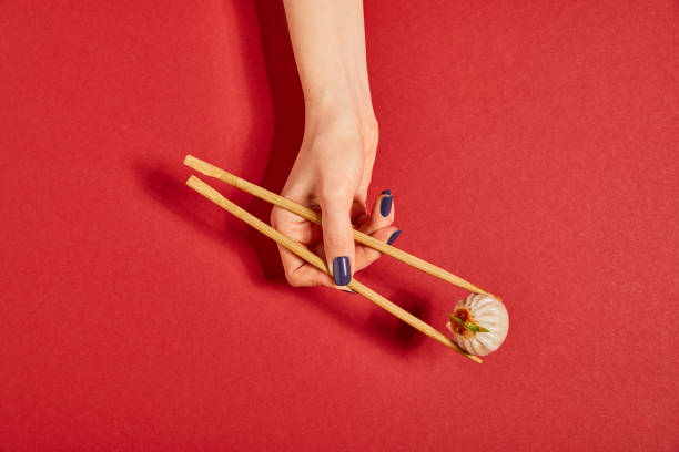 top view of woman holding chopsticks with steamed bun on red - hashis imagens e fotografias de stock