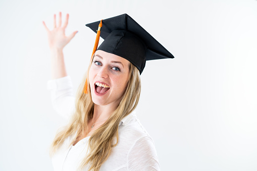 Girl with excited facial expression, wearing a graduation hat.