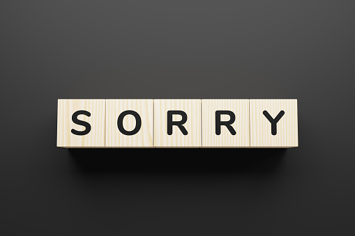 SORRY word made with wood building blocks. Word SORRY is made of wooden building blocks on gray background.