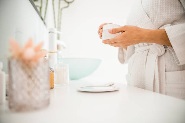 istock Female in bathrobe holding cosmetic face cream 1226955771