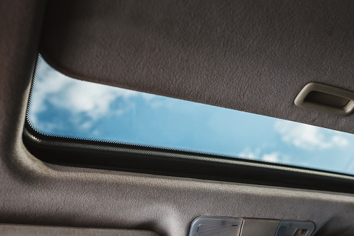 Blue sky through an open car sunroof - view from the passenger compartment