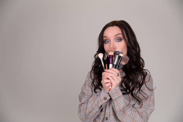 istock Girl makeup with brush cosmetics on a white gray background 1226957154