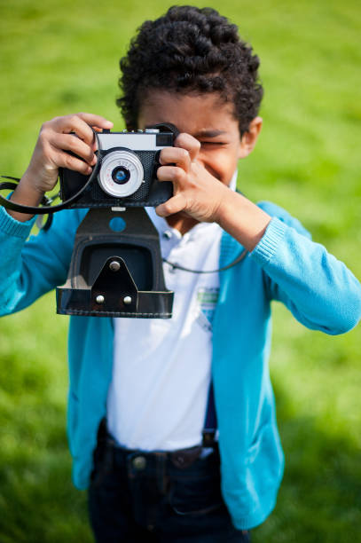 istock Little cute real black boy making pictures with a vintage camera. 1226960116