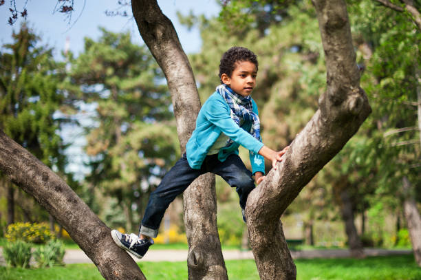 istock Little cute real black boy climbing on tree height. 1226960119