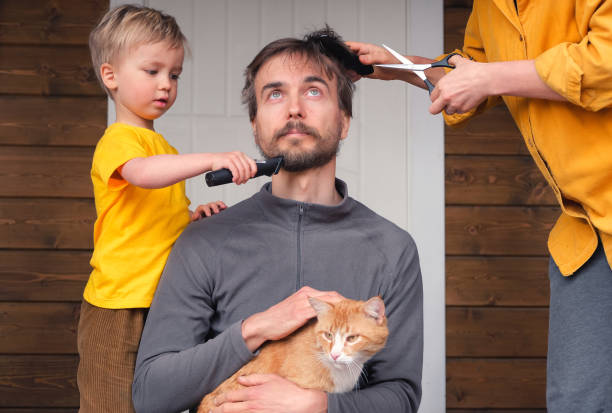 family haircut at home during quarantine lockdown, domestic hairdressers. mother cutting hair to father and little child boy cut dad beard with clipper. beauty and selfcare at home lifestyle. - child domestic cat little boys pets imagens e fotografias de stock