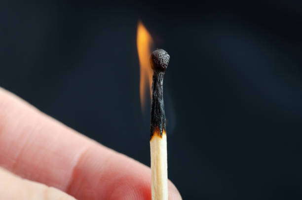 istock Burning match in hand against a black background. Close-up shot 1226961981