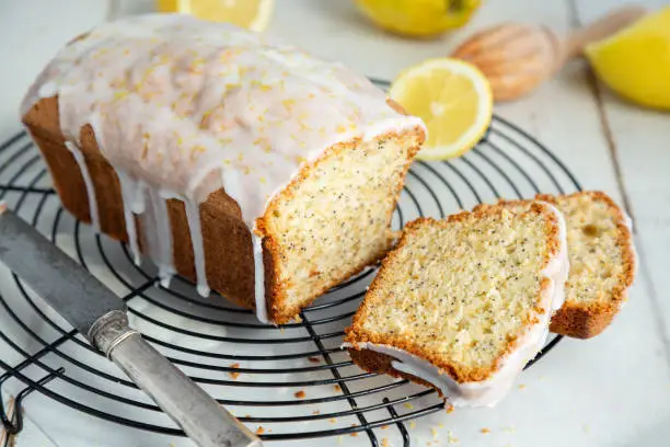 Glazed lemon pound cake loaf with poppy seed and lemon zest on a cooling rack
