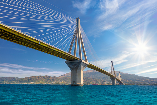 Amazing Modern Bridge against blue sky with sun. Rion-Antirion Bridge. The bridge connecting the cities of Patras and Antirrio, Greece