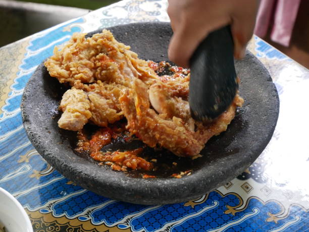 Making ayam geprek,  popular fusion dish of smashed southern fried chicken with topping of red chili relish. Ayam geprek is one of the favorite foods among young people of Indonesia. stock photo