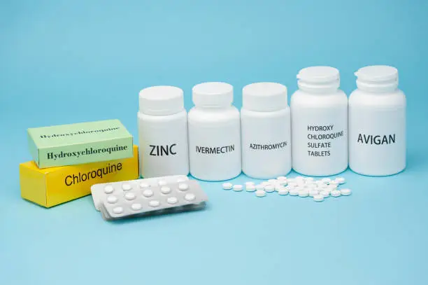 Chloroquine, Hydroxychloroquine Sulfate, Zinc, Ivermectin and Avigan. Some of the drugs currently used in the treatment of COVID-19. Blister pack and scattered pills. Isolated on blue background.