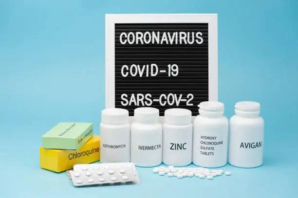 Chloroquine, Hydroxychloroquine Sulfate, Zinc, Ivermectin and Avigan. Some of the drugs currently used in the treatment of COVID-19. Blister pack and scattered pills. Writing board in the background.