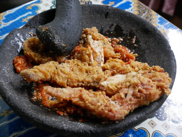 Making ayam geprek,  popular fusion dish of smashed southern fried chicken with topping of red chili relish. Ayam geprek is one of the favorite foods among young people of Indonesia. stock photo
