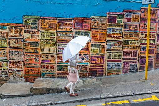 Central, Hong Kong - April 26, 2017: One Person With White Umbrella Walk in Front of Graffiti Art Gutzlaff Street in Soho, Central Hong Kong.
