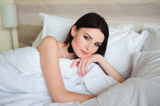 istock Happy young woman lying in bed and looking at camera 1226974971
