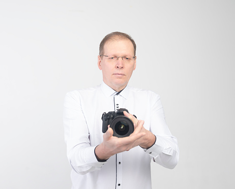careful and inconfident senior middle aged Photographer Holding Camera on white background