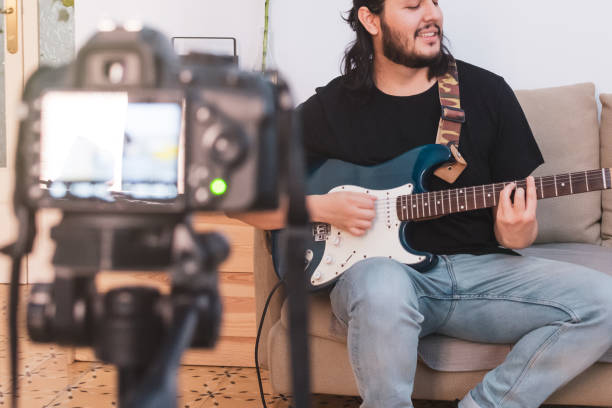 istock Young man recording an online guitar lesson video tutorial at home 1226978577