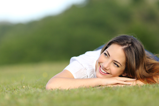 Happy woman lying on grass looking sideways on a park