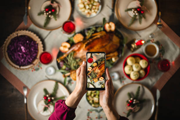 Photographing Christmas dinner with a smart phone Woman using her smart phone to photograph a typical German Christmas dinner. Female taking pictures of Christmas menu on table. roast dinner photos stock pictures, royalty-free photos & images
