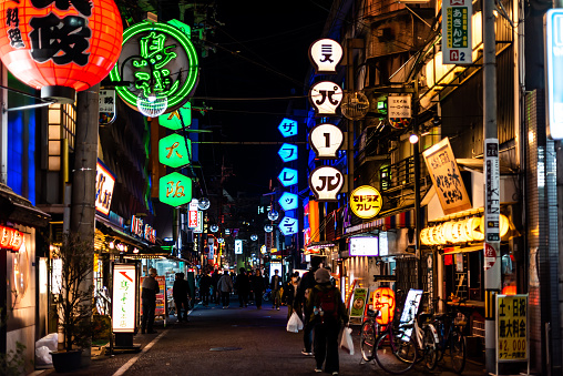 Osaka, Japan - April 13, 2019: Minami Namba famous street with people walking in dark night and illuminated red green neon buildings with red paper lanterns