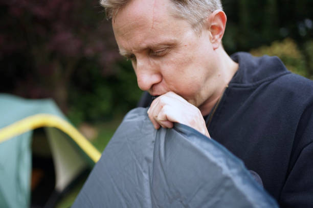 Close up of man blowing up a self inflatable sleeping pad for camping stock photo