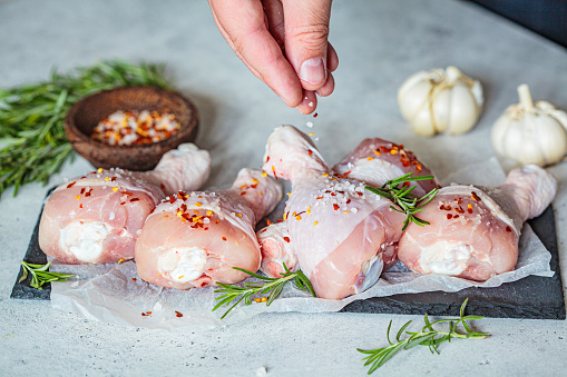 Raw chicken legs on a slate with spices, garlic and rosemary. Cooking food concept.