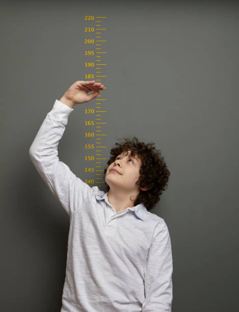 istock Cute boy is showing his height on a wall scale 1226991141