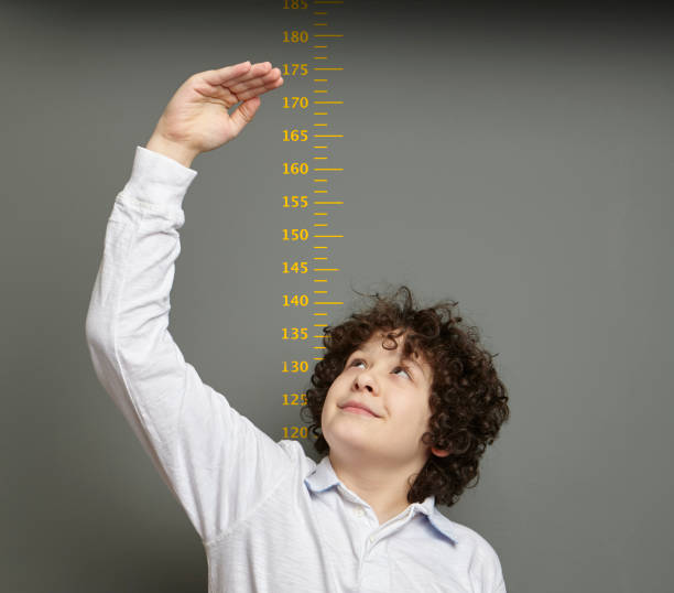 istock Cute boy is showing his height on a wall scale 1226991192