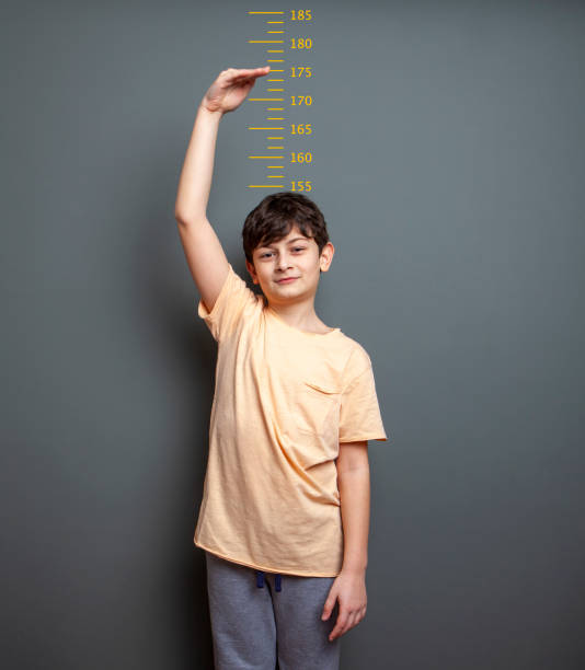 istock Cute boy is showing his height on a wall scale 1226991219