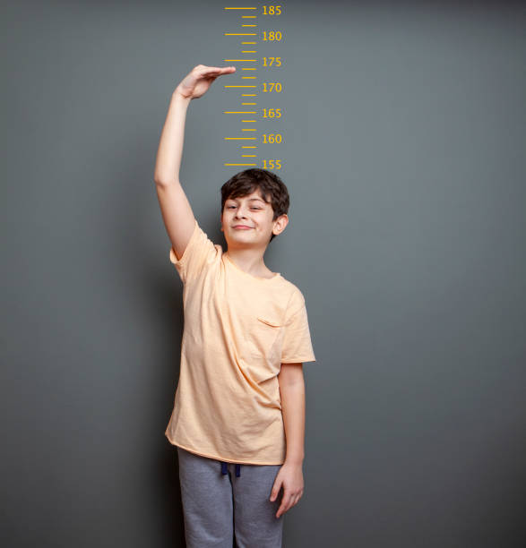 istock Cute boy is showing his height on a wall scale 1226991243
