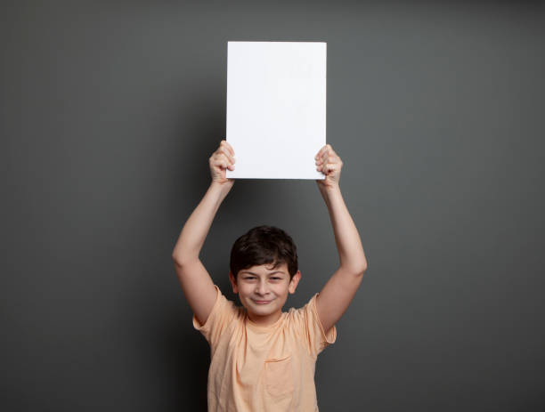 istock Cute boy is holding a blank page above his head 1226991332