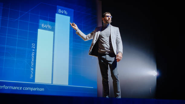 istock On-Stage Speaker Gives Presentation of Technological Device, Shows Infographics Animation on Big Screen. Auditorium Hall Live Event, Product Release, Start-up Conference. Low Angle 1226991384