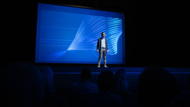 istock Startup Conference Stage: Speaker Presents New Product, Talks about Performance, Neural Networks, Artificial Intelligence, Big Data and Machine Learning. Live Business Event with Large Audience 1226991405