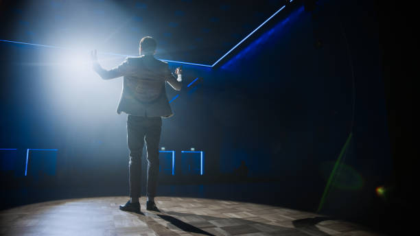 istock Famous Entertainer Gets on the Stage, Greets Audience, Starts Performance. Software Company Founder, Tech Marketing Guru Making a Pitch, Presentation Speaker Giving Talk. Cinematographic Shot 1226991444