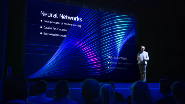 istock Computer Science Startup Conference: On Stage Speaker Does Presentation of New Product, Talks about Neural Networks, Shows New AI, Big Data and Machine Learning App on Big Screen. Live Event 1226991457